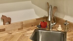 A kitchen with white cabinets, a stainless steel sink, wooden countertops, and a small decorative horse figure. - Willow Studio near Vashon Town (Vashon)