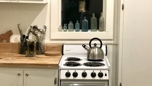 A kitchen with a stove, a window with bottles, and a rooster decal. - Willow Studio near Vashon Town (Vashon)