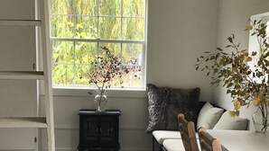 A room with a window, a small table with a vase, a bench, and a chair. - Willow Studio near Vashon Town (Vashon)
