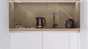 A compact kitchen with a marble backsplash, a coffee maker, and a toaster.