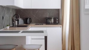 A modern kitchen with white cabinets, a marble backsplash, and wooden stools.
