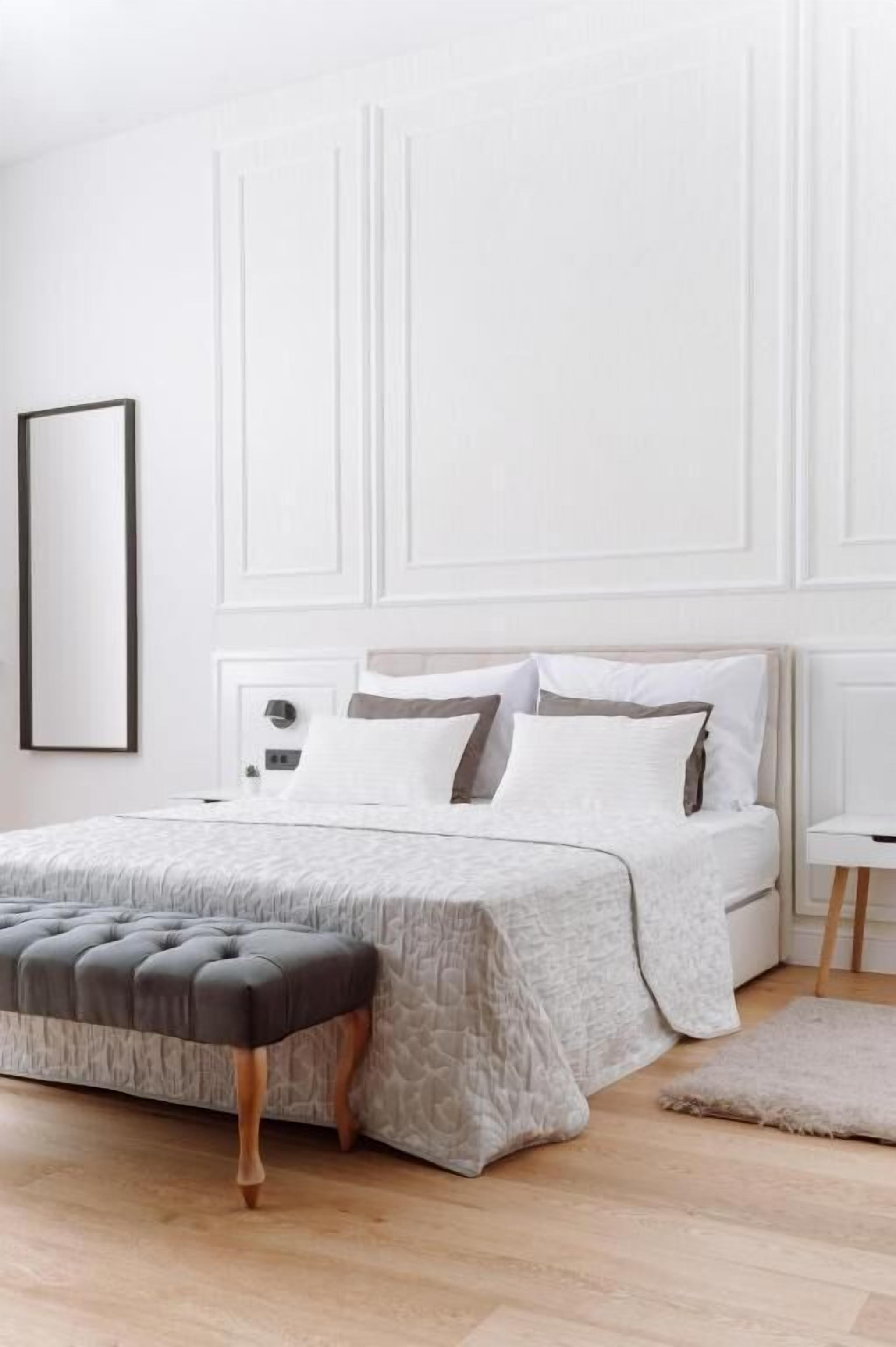 A neatly arranged bedroom with a bed, a bedside table, and a large window.
