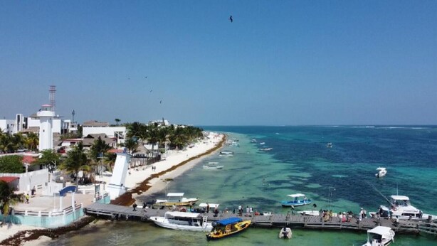 A coastal town with a pier, boats, and a beach.