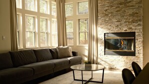 A living room with a stone fireplace, a sofa, and a coffee table. - Upscale, Nature Views, Family Retreat for a great Mountain Getaway (Flagstaff)