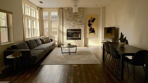 A living room with a fireplace, a sofa, a dining table with chairs, and a chandelier. - Upscale, Nature Views, Family Retreat for a great Mountain Getaway (Flagstaff)