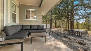 A covered outdoor seating area with a sofa, coffee table, and dining table. - Upscale, Nature Views, Family Retreat for a great Mountain Getaway (Flagstaff)