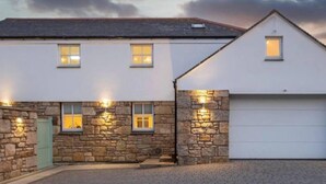 A two-story house with a stone facade, a garage, and a paved driveway.