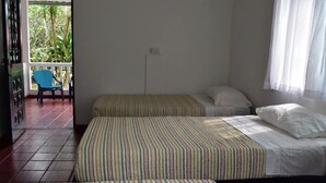 Quarto com duas camas, uma cadeira e vista para o verde lá fora.