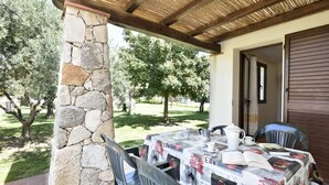 Un patio al aire libre con un pilar de piedra, una mesa con mantel floral y sillas.