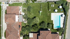 Vista aérea de una zona residencial con varias casas, una piscina y un césped verde.