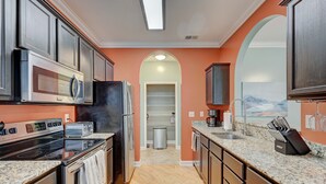 A modern kitchen with stainless steel appliances, granite countertops, and dark wooden cabinets.