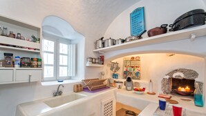Une cuisine avec des armoires blanches, une fenêtre, un évier, une cuisinière et divers ustensiles de cuisine.