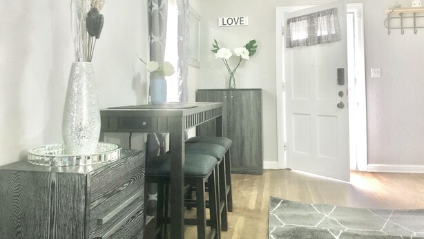 A dining area with a wooden table, chairs, a decorative vase, and a wall-mounted sign that says "LOVE". - Brilliant Bungalow (Dayton)