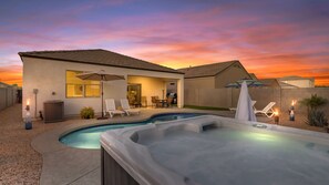 A backyard with a swimming pool, hot tub, and outdoor seating area.