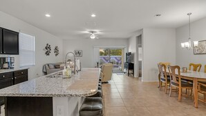 A spacious kitchen with a large island, a dining area with wooden chairs, and a flat-screen TV mounted on the wall. - East Valley Peaceful Oasis w/PRIVATE Pool that is HEATED at no extra cost (Florence)