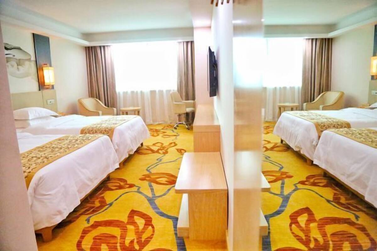 A hotel room with two beds, a TV, a desk, and a chair.