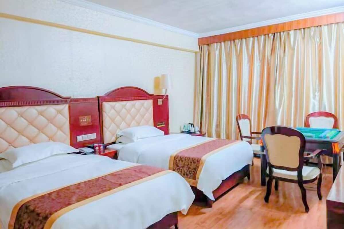 A hotel room with two beds, a desk, and a chair.