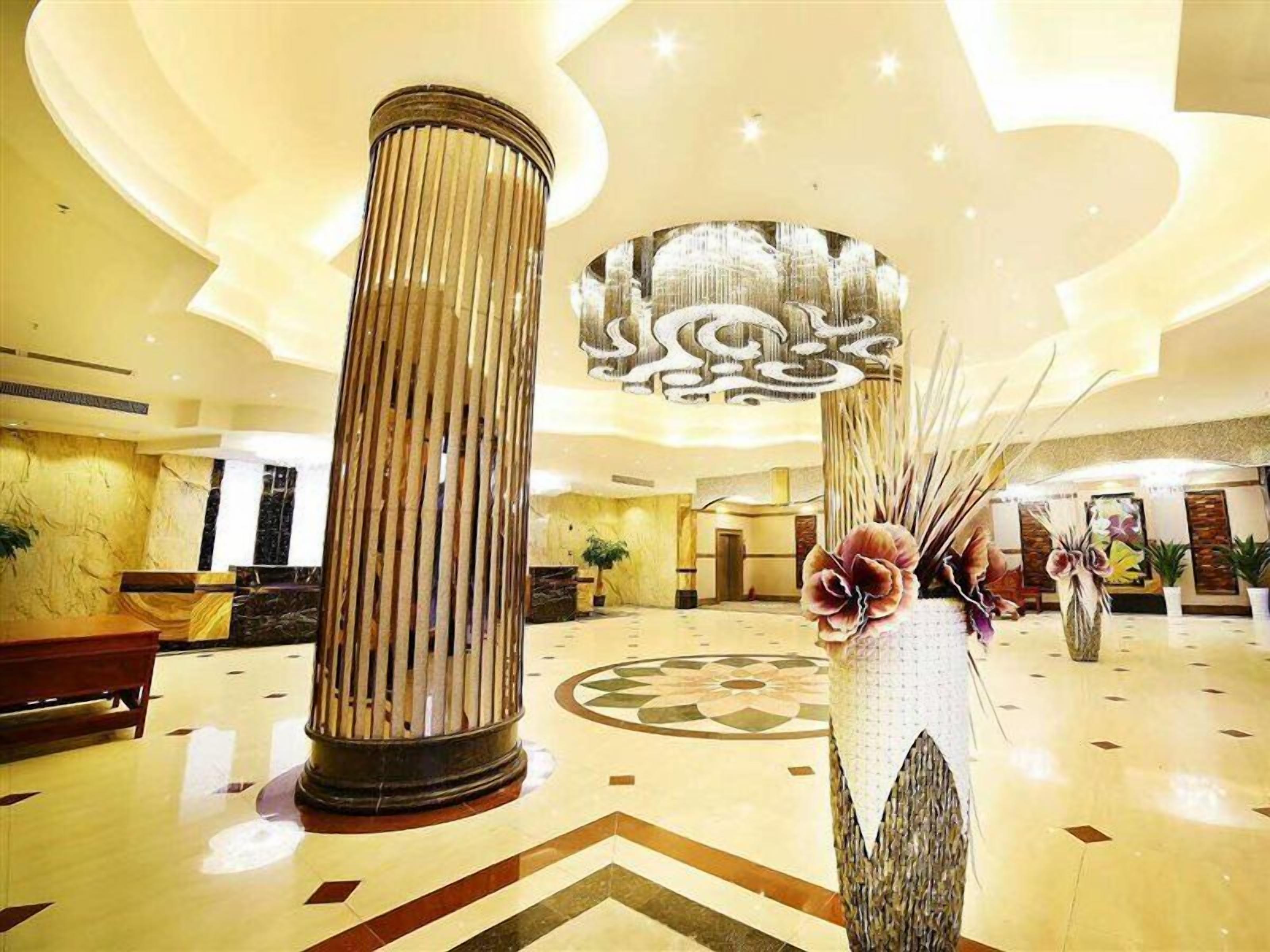 A lobby with a large column, a decorative vase, and a chandelier.