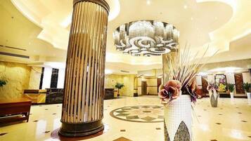 A lobby with a large column, a decorative vase, and a chandelier.