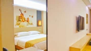 A hotel room with a bed, a bedside table, a mirror, and a wall with a guitar and butterfly decoration.