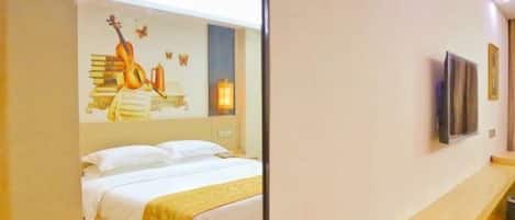 A hotel room with a bed, a bedside table, a mirror, and a wall with a guitar and butterfly decoration.