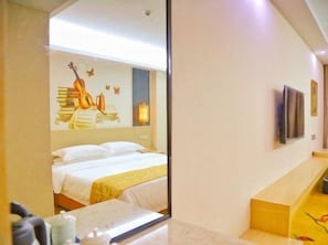 Una habitación de hotel con cama, mesita de noche, espejo y una pared decorada con una guitarra y una mariposa.