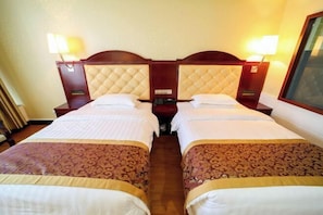 A hotel room with two beds, each with a headboard, bedside tables, lamps, and a small nightstand. - Bobai Baolilai Hotel (Bobai)