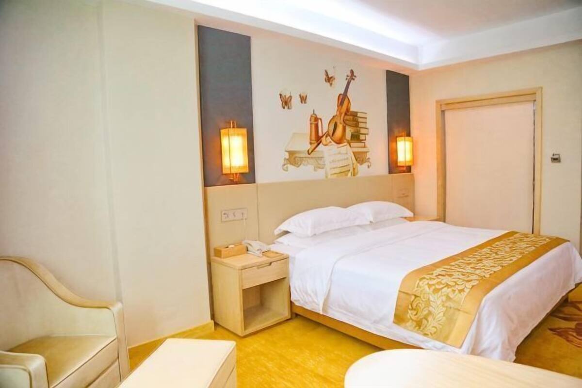 A hotel room with a bed, bedside table, lamp, and a chair.