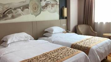 A hotel room with two beds, a large floral artwork on the wall, a chair, and a small table.