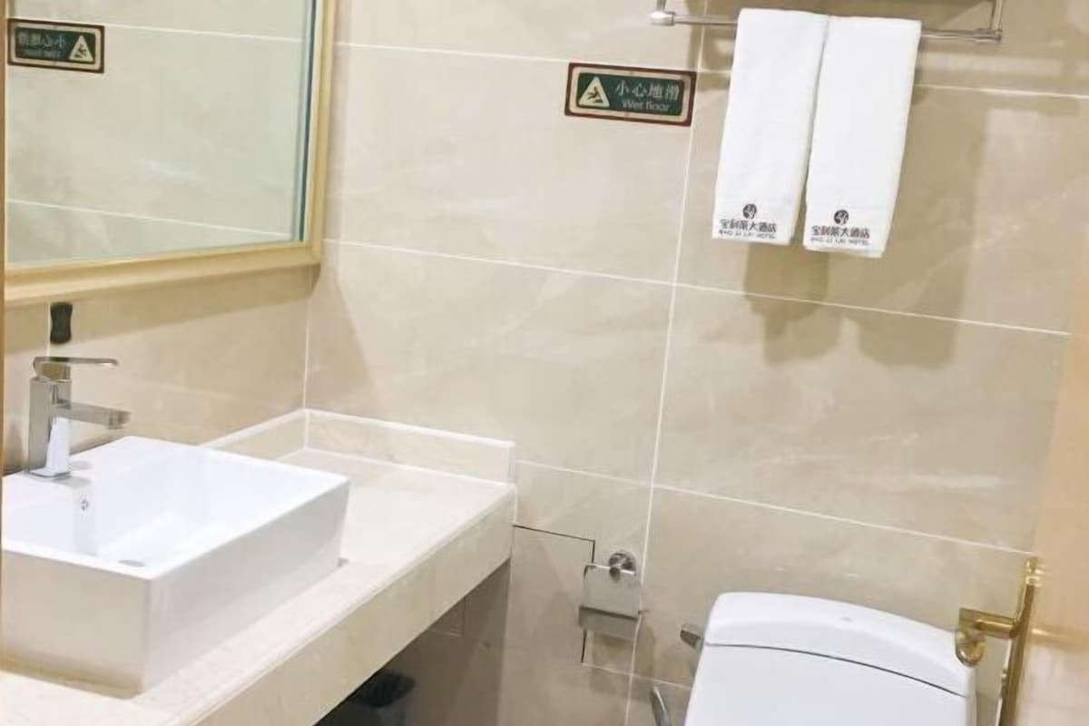 A bathroom with a white sink, a mirror, and a toilet. There are two towels hanging on a rack.