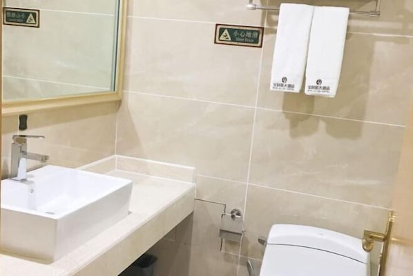 A bathroom with a white sink, a mirror, and a toilet. There are two towels hanging on a rack. - Bobai Baolilai Hotel (Bobai)