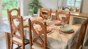 Een eethoek met een tafel voor vier personen, omringd door houten stoelen. Een grote spiegel hangt boven de tafel, waardoor de ruimte wordt weerspiegeld.