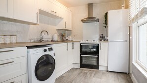 Een moderne keuken met witte kasten, een ingebouwde wasmachine, een dubbele oven en een koelkast.