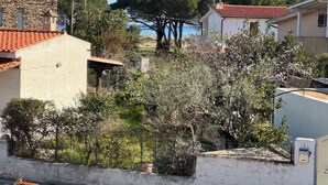 A residential area with stone and tiled buildings, a fenced garden, and a view of a hill with trees. - Ideal family home 200 meters from the beach and in Tepilora Park!!! (Posada)