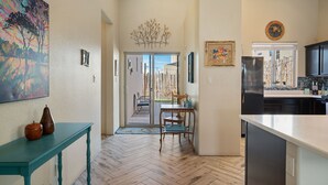 A kitchen with a modern refrigerator, a dining area with a table and chairs, and a hallway leading to a door. - Luxurious Open Concept Home with Fabulous Backyard Entertainment Area (Santa Fe)