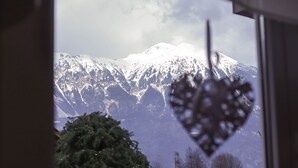 Vista de la montaña a través de una ventana decorada con un adorno con forma de corazón.