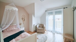 Un dormitorio con cama, una silla, un radiador y una ventana con cortinas.