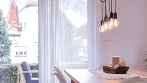 Un comedor con una mesa de madera, sillas blancas y bombillas colgantes.