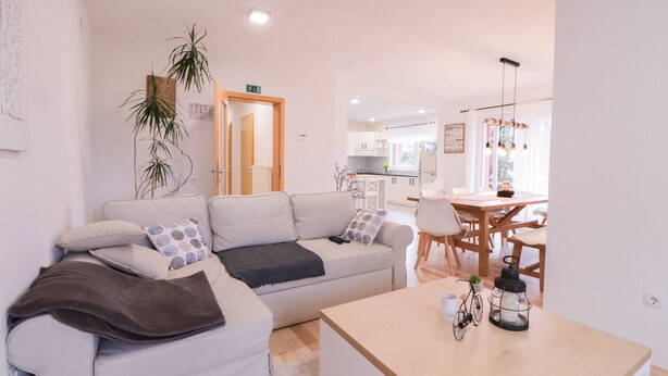 Una sala de estar moderna con un sofá, una mesa de centro y un comedor con mesa y sillas.
