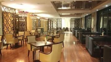 Een ruim restaurant met meerdere eettafels en stoelen, hoge plafonds en decoratieve wandpanelen.