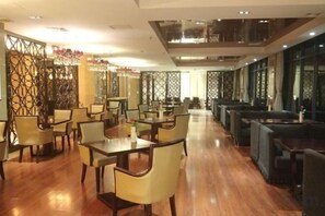 A spacious restaurant with multiple dining tables and chairs, high ceilings, and decorative wall panels. - Lianhua Hotel (Xiangcheng)