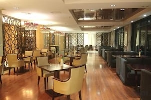 Un restaurante espacioso con numerosas mesas y sillas, techos altos y paneles decorativos en las paredes.