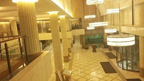 Een ruime lobby met hoge plafonds, grote zuilen en moderne kroonluchters.