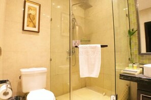 A bathroom with a glass-enclosed shower, a toilet, and a sink. - Lianhua Hotel (Xiangcheng)