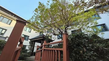 A gated entrance with a wooden fence, a tree, and a building in the background.