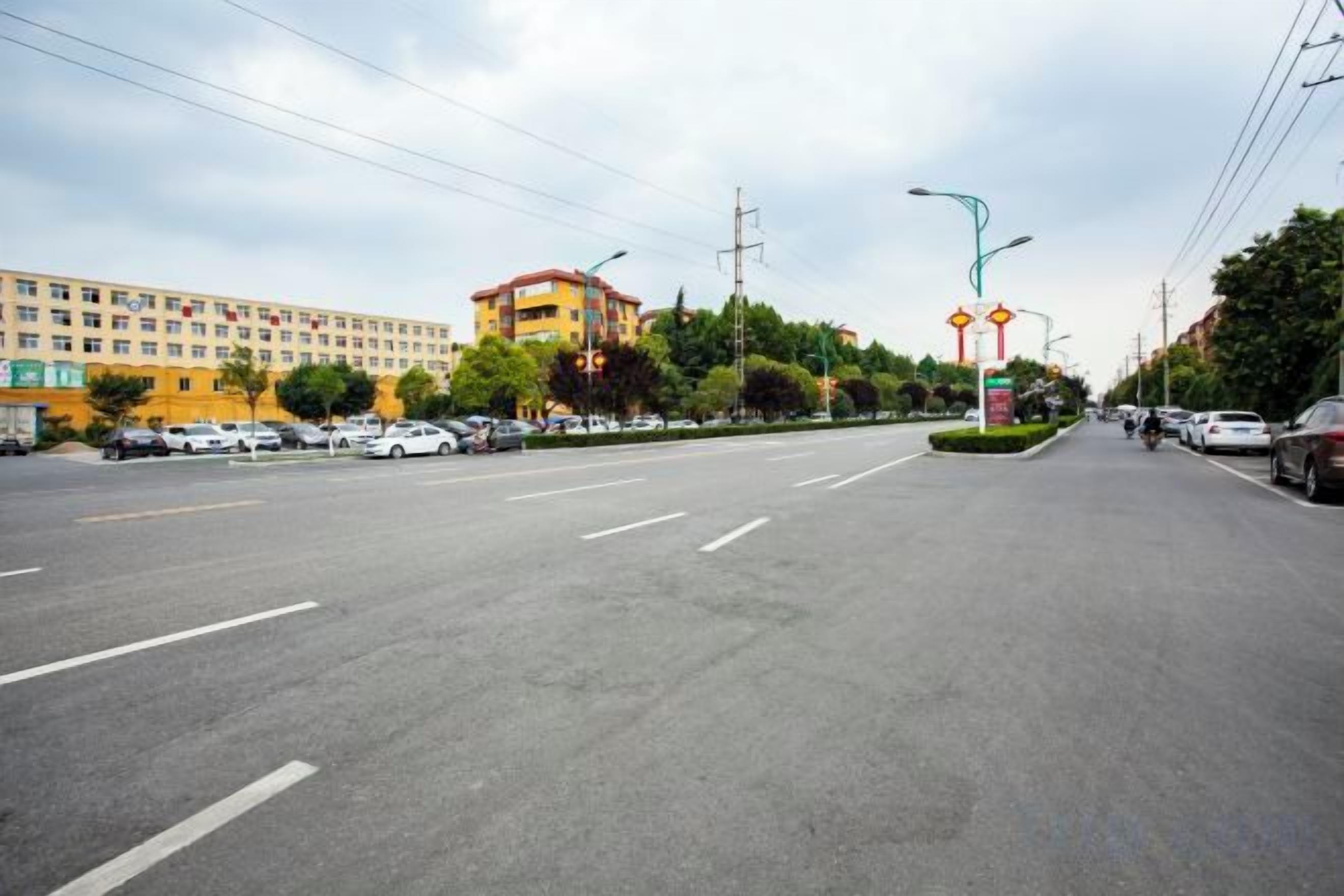 Una amplia carretera con varios carriles, un semáforo y un edificio de fachada amarilla al fondo.