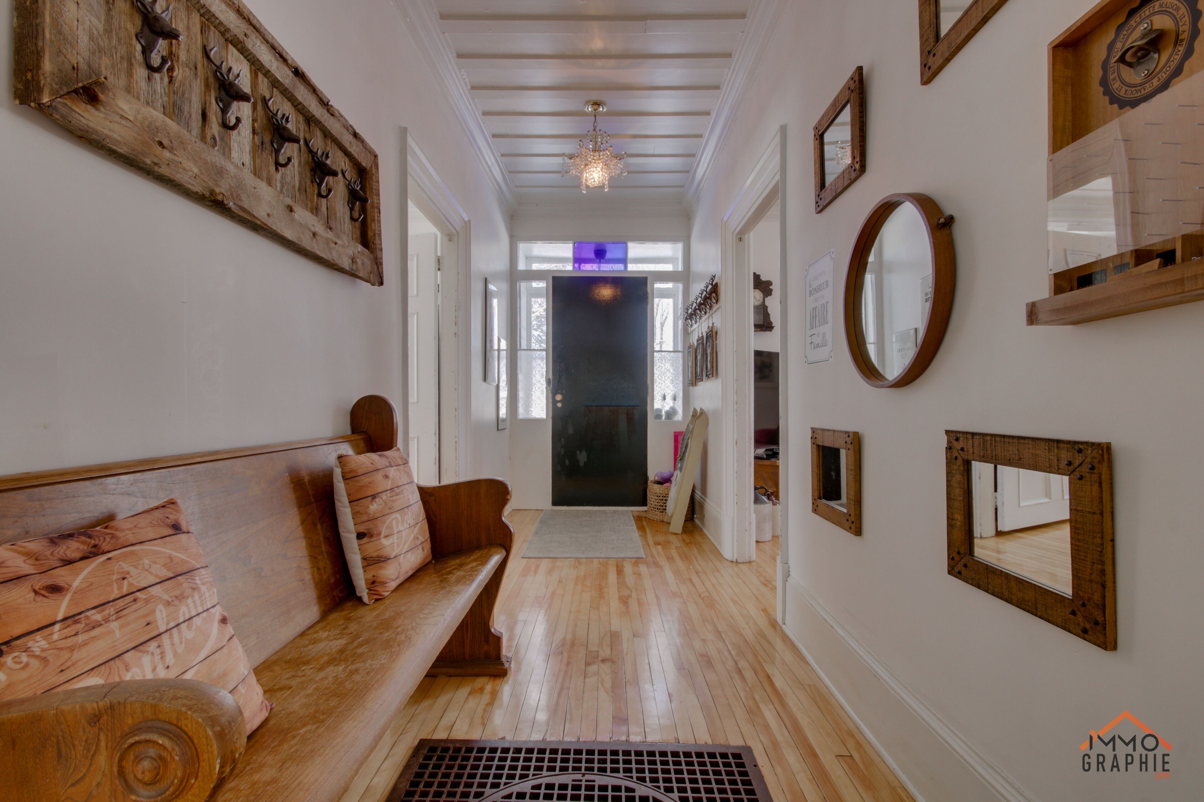 Un pasillo con un banco de madera, un espejo decorativo y un adorno de pared de madera.