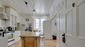 Een keuken met witte kasten, een houten kookeiland en een kroonluchter.