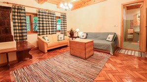 A cozy living room with a wooden ceiling, a sofa, a small table, and a patterned rug. - House Alpine Rose - Apartment Toni (Mojstrana)