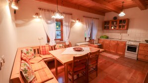 A cozy kitchen with wooden cabinets, a dining table, and a built-in bench with cushions. - House Alpine Rose - Apartment Toni (Mojstrana)